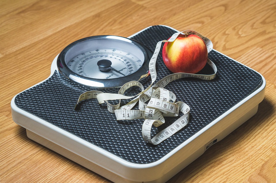 apple and measuring tape on scale